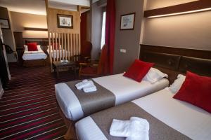 Hotel De L'univers في سان مالو: غرفة فندق بسريرين ومخدات حمراء
