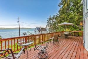 a wooden deck with chairs and tables and an umbrella at Seal Rock Cottage in Brinnon