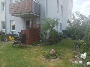 a house with a yard with a chair and a balcony at Atrakcyjny apartament z dużym ogrodem in Gdańsk