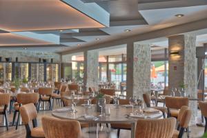 a dining room with tables and chairs and windows at Hôtel du Golf de l'Ailette, The Originals Relais in Chamouille
