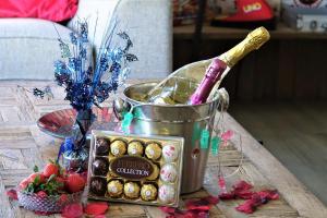 a bucket of candy and a bottle of champagne on a table at Lakeland Lodge with private Hot Tub and fishing in Hatfield Peverel