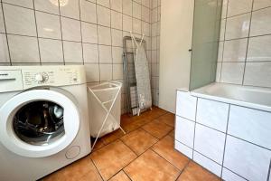 eine Waschküche mit einer Waschmaschine und einer Badewanne in der Unterkunft Cozy Apartment Krefeld in Krefeld