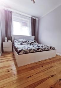 een slaapkamer met een bed en een houten vloer bij Apartamenty Pszczew Krzysztof Michna Lubuskie Mazury Apartament "MAJA" in Pszczew