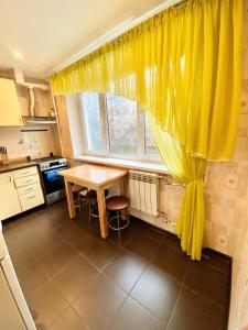 a kitchen with a table and a yellow curtain at Квартира на Воскресенці, поруч метро Лівобережна, Інститут Серця, МВЦ in Kyiv