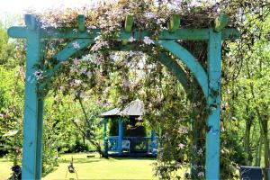 un arco con cenador en un parque con flores en Lakeland Lodge with private Hot Tub and fishing, en Hatfield Peverel