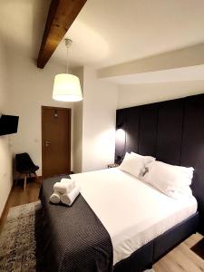 a bedroom with a large white bed with a black headboard at Arriaga Douro House in Peso da Régua