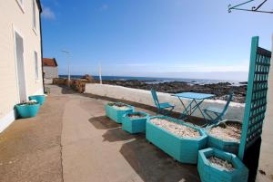a patio with blue chairs and a table on the beach at Westshore House- fabulous waterfront home Fife in Pittenweem