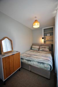 a bedroom with a bed and a mirror and a dresser at Auld Fishers Catch- homely apartment near the sea in Anstruther