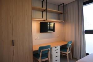 a room with a desk with two chairs and a tv at MEU STUDIO in Gandra