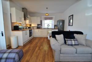 ein Wohnzimmer mit einem Sofa und einer Küche in der Unterkunft Turnstone- beautiful coastal home Pittenweem in Pittenweem