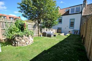 a yard with a fence next to a house at Turnstone- beautiful coastal home Pittenweem in Pittenweem