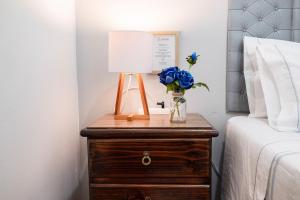 a bedside table with a lamp and a vase of blue roses at Hab Pequeña baño compartido La Paz 4 in Lima