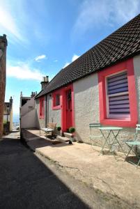 uma casa vermelha e branca com uma porta vermelha em Dookers Nook- Quirky coastal cottage Pittenweem em Pittenweem