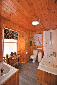 uma casa de banho em madeira com uma banheira, um WC e um lavatório. em Dookers Nook- Quirky coastal cottage Pittenweem em Pittenweem