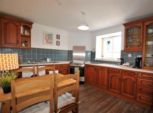 uma cozinha com armários de madeira, uma mesa e um lavatório em Dookers Nook- Quirky coastal cottage Pittenweem em Pittenweem