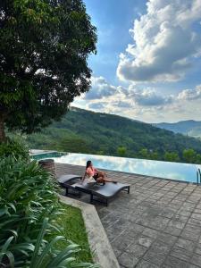 een man op een bankje naast een zwembad bij Leaf Olu Ella in Yatiyantota