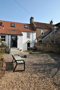 eine Bank, die im Hof eines Hauses sitzt in der Unterkunft Woods Neuk-stunning character cottage East Neuk in Pittenweem