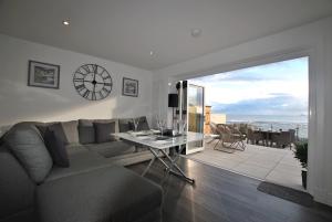 ein Wohnzimmer mit einem Sofa und einem Tisch mit einer Uhr in der Unterkunft The Wendy House-seafront cottage incredible views in Anstruther