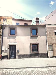 a white building with a black door and windows at Arriaga Douro House in Peso da Régua