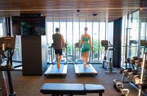 a man and a woman walking on treadles in a gym at Vibe Hotel Adelaide in Adelaide