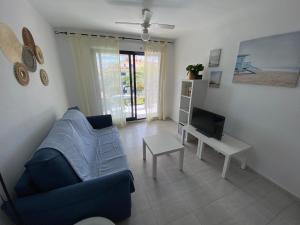 uma sala de estar com um sofá azul e uma televisão em Apartamentos Porta Mediterranea Altamar em Alcossebre