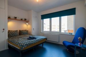 a bedroom with a bed and a chair and a window at Spacious family flat near the beach (6-8 pers) in Koksijde