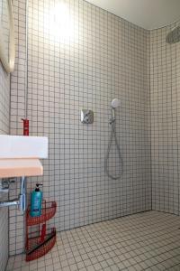 La salle de bains est pourvue de carrelage blanc, d'une douche et d'un lavabo. dans l'établissement Spacious family flat near the beach (6-8 pers), à Coxyde