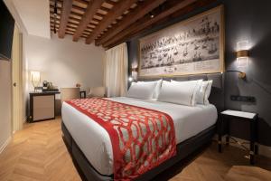 a hotel room with a large bed and a painting on the wall at Áurea Casa Palacio Sagasta by Eurostars Hotel Company in Cádiz