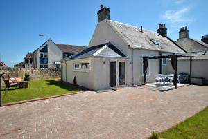 a white house with a patio in the yard at Shore Cottage Anstruther- stylish home by the sea in Anstruther