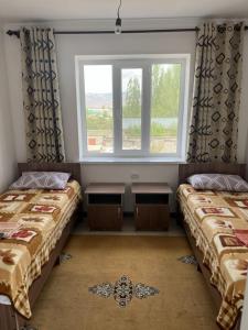 two beds in a room with a window at Guest House Baytur in Kochkor