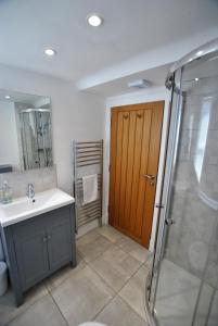 baño con lavabo, ducha y puerta en Shore Cottage Anstruther- stylish home by the sea, en Anstruther