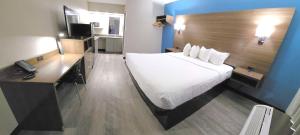 um quarto com uma grande cama branca e uma secretária em SureStay Studio by Best Western Victoria em Victoria
