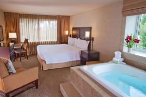 um quarto de hotel com uma cama grande e uma banheira em Eastgate Hotel - BW Signature Collection em Bellevue