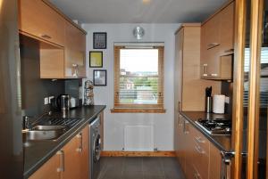 a kitchen with wooden cabinets and a sink at Jessies Selkie- homely apartment in East Neuk in Anstruther