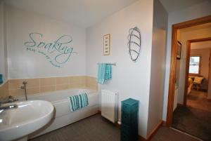 a bathroom with a tub and a sink and a bath tub at Jessies Selkie- homely apartment in East Neuk in Anstruther +12 photos