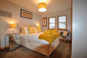 a bedroom with a bed with a yellow blanket on it at Jessies Selkie- homely apartment in East Neuk in Anstruther