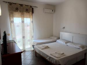 1 dormitorio con 2 camas, TV y ventana en Le Porte del Sole, en Girasole