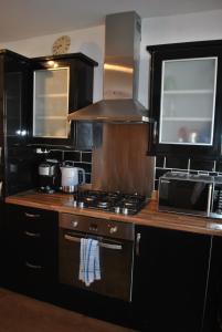 a kitchen with a stove and a microwave at Sand And Sea Cottage- lovely family home Crail in Crail