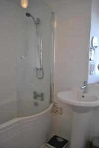 a white bathroom with a shower and a sink at Sand And Sea Cottage- lovely family home Crail in Crail