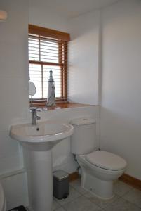 a white bathroom with a toilet and a sink at Sand And Sea Cottage- lovely family home Crail in Crail