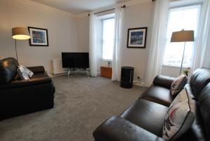 a living room with a leather couch and a television at Harbour House- home from home in Pittenweem in Pittenweem