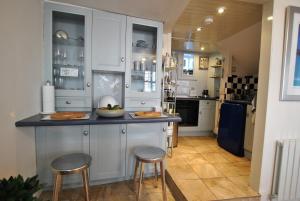 a kitchen with white cabinets and two stools at a counter at Oyster Cottage- relaxing retreat by the sea in Saint Monance