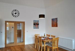 a dining room with a table and chairs and a clock at Academy Apartment Anstruther- stunning luxury home in Anstruther