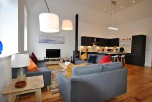 a living room with blue couches and a kitchen at Academy Apartment Anstruther- stunning luxury home in Anstruther