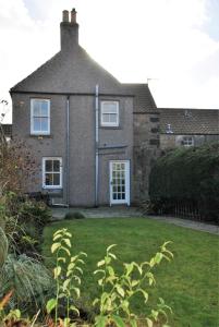 una casa de ladrillo con un patio de hierba delante de ella en Willow Cottage- charming cottage in East Neuk, en Pittenweem