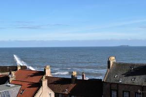 a view of the ocean from the roofs of buildings at The Loft- charming character cottage in East Neuk in Anstruther