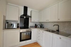 a white kitchen with white cabinets and a sink at Creel Cottage- stylish cottage near the sea in Anstruther