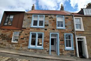 a brick house with white windows and a red roof at Creel Cottage- stylish cottage near the sea in Anstruther
