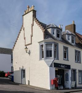 a large white building with a store on a street at Crail Posthouse - 19th Century traditional house in Crail