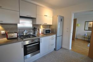 uma cozinha com armários brancos, um fogão e um frigorífico em The Neuk- contemporary coastal apartment em Anstruther